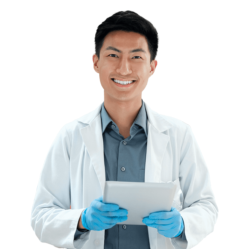 A male doctor in a white coat holding a tablet computer, looking at the screen with a focused expression.