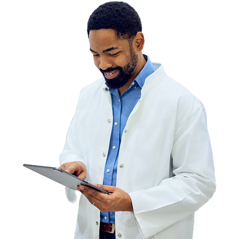 A male doctor in a white coat holding a tablet computer, looking at the screen with a focused expression.